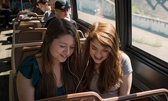 Two girls listening to music on a bus