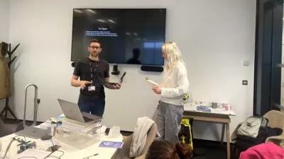 A man and a woman presenting information on a big screen