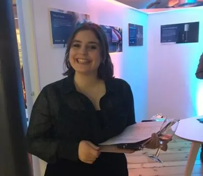 A photo of Charlotte holding a clipboard and a Champagne flute