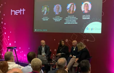 A panel of leading healthcare professionals sat around a table in front of a pink background.