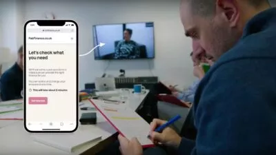 A photo of stakeholders watching user research in a separate room. There's a screenshot of a prototype on a phone saying 'Let's check what you need. We'll ask some quick questions to make sure we provide the right finance for you. .You can review and change your answers at any time. This will take about 2 minutes.' There's a button saying 'Get started'