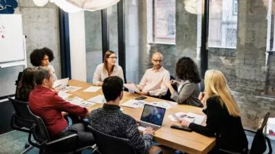 A photo of 8 people sat around a table talking