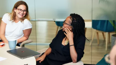 CXPartners employees, Sarah and Kabi, sat at a table having a conversation.
